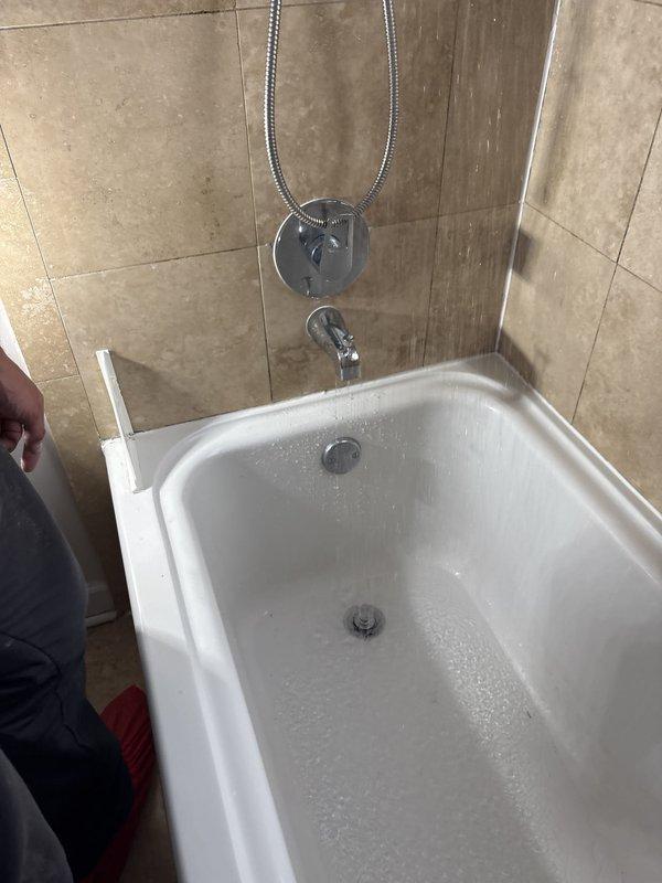 Responded to report of leak behind shower in bathroom with alcove-style tub installation. Upon inspection, identified severely corroded copper supply pipe with visible perforation causing water leakage. Removed damaged section of pipe showing extensive rust deterioration and compromised structural integrity. Replaced failed copper piping with new materials to restore proper water supply function and eliminate leak condition.