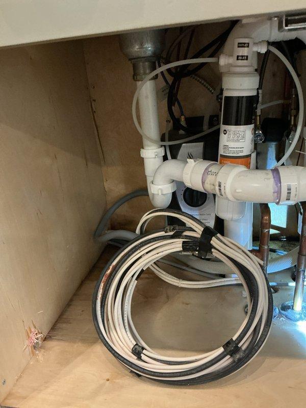 Responded to service call for leak under kitchen sink. Upon inspection, identified leak originating from P-trap assembly and supply line connections beneath the cabinet. Disassembled existing white PVC P-trap configuration and inspected all drain components for damage and proper seal integrity. Examined water filtration system connections and supply lines for potential leak sources. Replaced worn washers and gaskets on P-trap connections and tightened all compression fittings to manufacturer specifications. Verified flexible supply lines for faucet were properly secured and free from damage. Tested all plumbing connections under pressure to confirm leak was eliminated. Cleaned work area and verified proper drainage function before completing service.