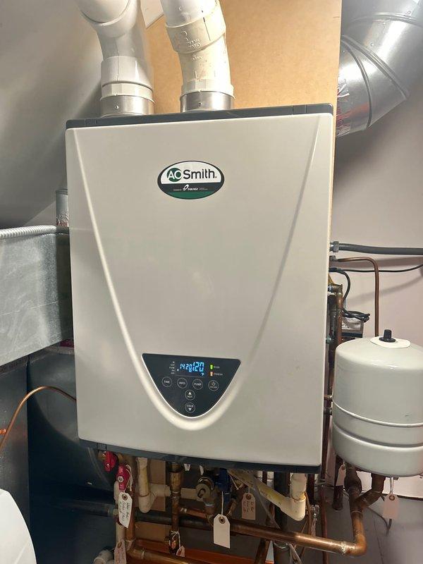 Performed comprehensive maintenance service on AO Smith tankless water heater unit. Inspected digital control panel displaying operational temperature of 140°F and verified all control functions operating properly. Examined complete plumbing assembly including copper supply lines, PVC venting system, expansion tank, and associated shut-off valves for proper operation and potential leaks. Verified drain pan placement and condition beneath equipment for adequate leak protection. Confirmed all system components, connections, and safety devices functioning within manufacturer specifications.