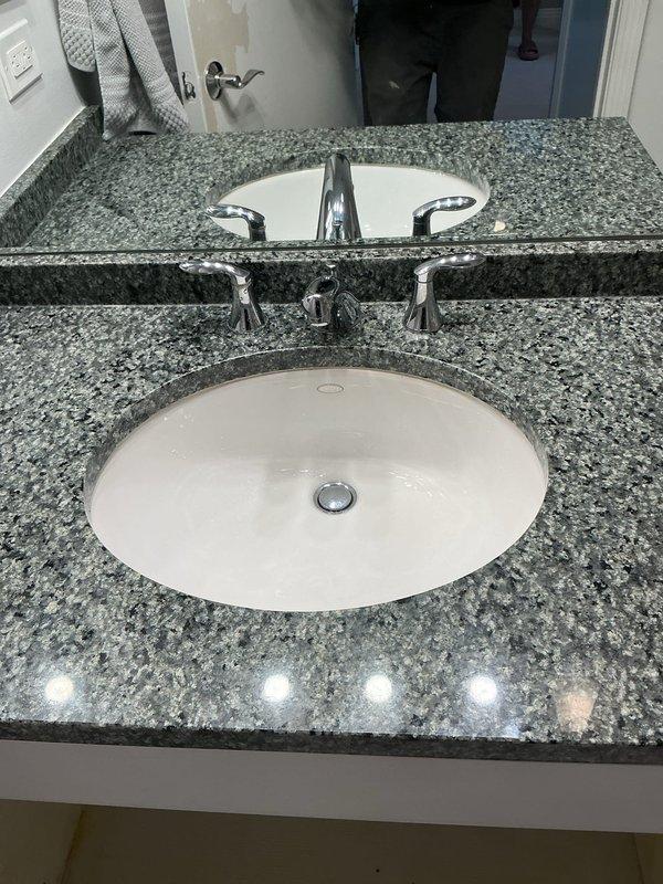 Replaced four aging faucets throughout the residence with customer-supplied fixtures, including installation of a three-handle chrome faucet assembly with center spout on a granite vanity countertop with undermount sink. Installed new drain assemblies and P-traps, connected water supply lines, and tested all fixtures for proper operation and leak-free performance. Repaired leaking exterior hose bibb in garage by replacing damaged anti-siphon valve components where internal fixture parts had broken off, restoring full functionality to the outdoor water supply.