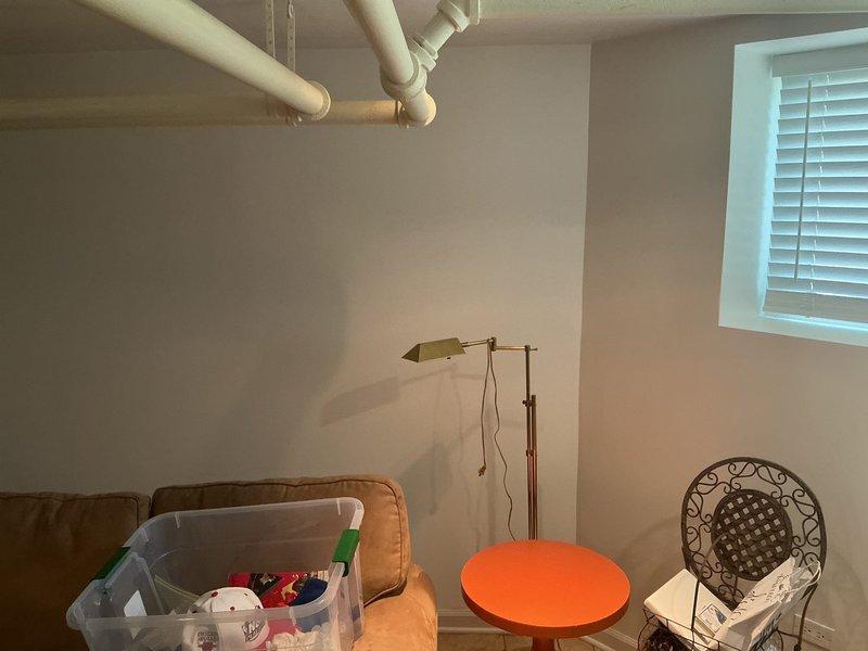 Installed PRIER quarter-turn valve assembly with brass body and green handle control in basement area. Valve features 90-degree operational mechanism with chrome-capped top section and copper pipe connection, providing reliable water flow control for the plumbing system.