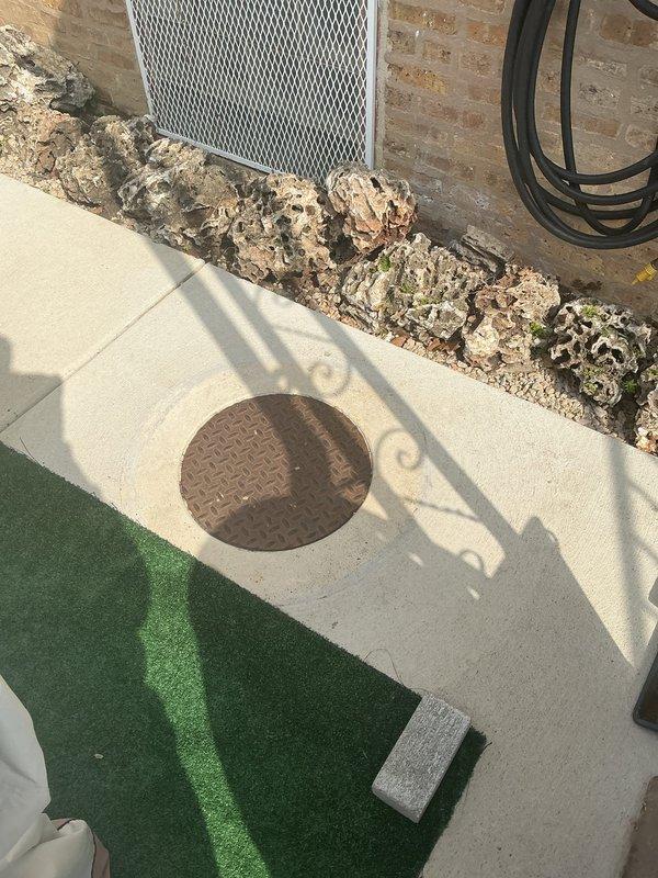 Completed plumbing repair service at outdoor patio area involving inspection and maintenance of drainage system components. Serviced circular floor drain with diamond plate grate embedded in concrete pad, ensuring proper functionality and clearing any obstructions to maintain optimal water flow from the patio surface.