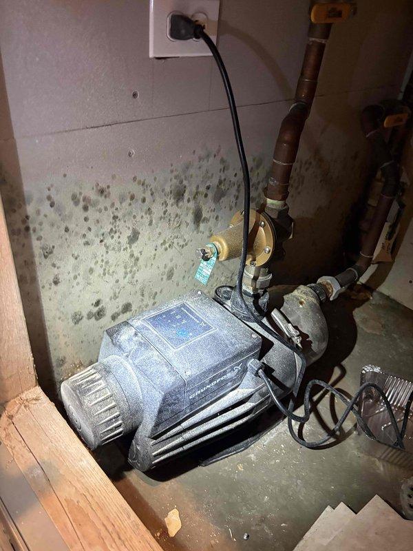 Responded to reported water leak in downstairs utility room affecting adjacent garage area. Upon inspection, identified failed seal on booster pump system responsible for transferring water to upper floor levels. Pump unit showed signs of prolonged moisture exposure with visible water staining on concrete floor and significant mold growth on surrounding walls, consistent with reported two-week leak duration. Assessed copper piping connections, pressure gauges, and brass fittings for integrity. Documented extensive water damage to utility room surfaces and pump installation area. Photographed existing conditions including deteriorated wall surfaces, floor staining, and overall pump configuration for service records. Provided recommendations for pump seal replacement, mold remediation of affected wall surfaces, and evaluation of drainage solutions to prevent future water accumulation in utility space.