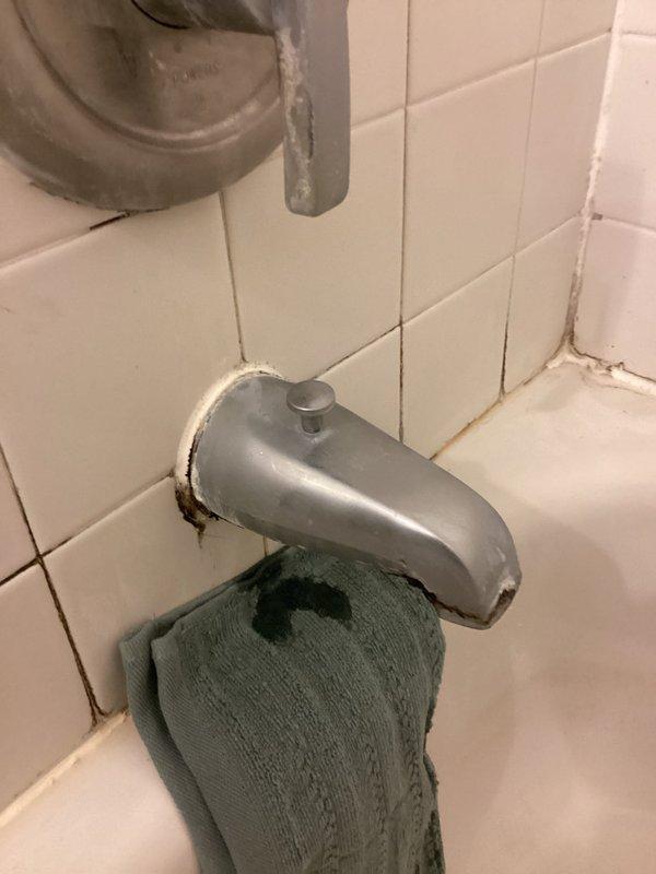 Completed comprehensive plumbing inspection of all valves and drains throughout the property to assess repair needs and provide accurate estimates. Examined bathroom bathtub fixtures, including brushed nickel faucet assembly with single lever handle and chrome tub spout with diverter button, noting visible deterioration around spout base connection with gaps in caulking seal and signs of water exposure. Documented aging grout lines with discoloration, brownish staining, and accumulated buildup around tile work, indicating potential moisture intrusion issues requiring attention.