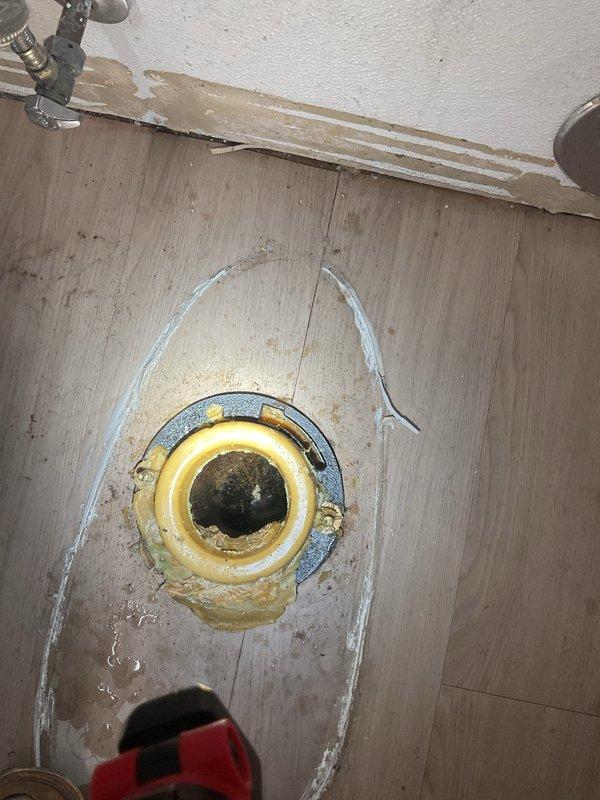 Conducted comprehensive drain and sewer assessment for commercial restroom facility experiencing plumbing issues. Inspection revealed active water leakage at toilet base with visible moisture staining on vinyl flooring, indicating compromised wax ring seal or flange connection. Evaluated exposed water supply lines, shutoff valves, and brass fixtures behind toilet for proper operation and potential leak sources. 

Assessed floor drain assembly installed in subflooring, noting weathered plywood surface and existing caulk seal around drain flange. Documented condition of drain components including inner opening, brass ring, and metallic collar for permanent repair recommendations. Photographed all affected areas including ADA-compliant accessible restroom features, exposed plumbing connections, and areas of water damage for estimate documentation. Scheduled follow-up appointment to present permanent solution options and implement necessary repairs to resolve water intrusion issues and res