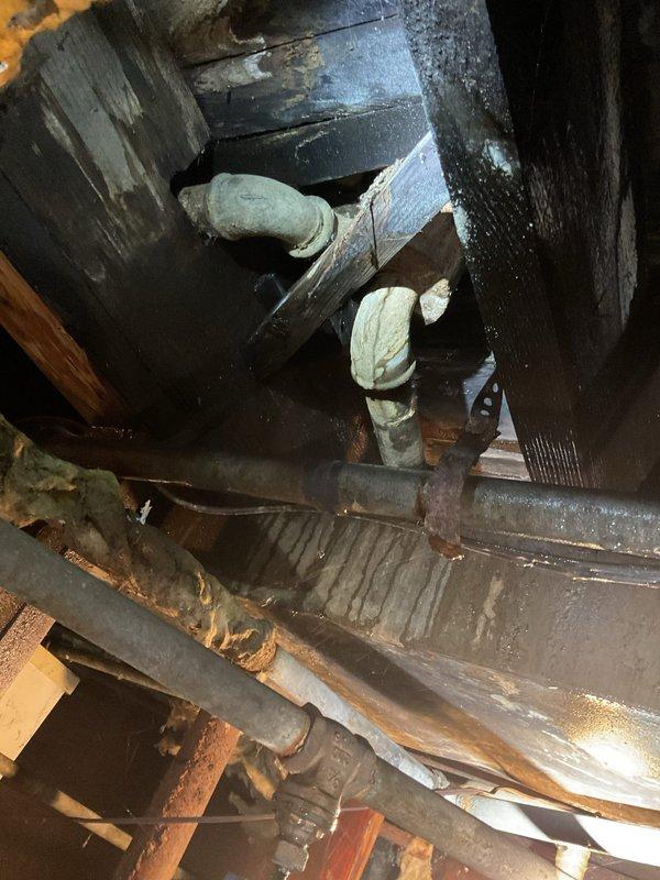 Replaced bathtub waste and overflow assembly including new brass drain pipes, chrome overflow cover plate with toggle lever mechanism, and perforated drain strainer. Inspected existing plumbing connections in confined access area and addressed corroded metal strapping and aged insulation on adjacent water supply lines to ensure proper drainage function and prevent future leaks.
