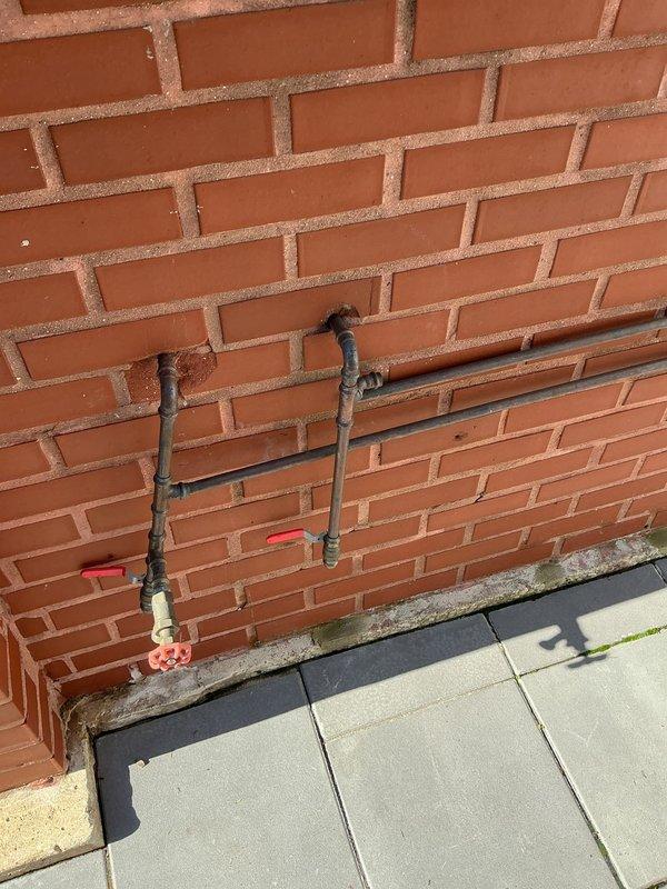 Installed exterior water supply system with new piping configuration including PVC and copper lines, mounted multiple shut-off valves with control handles at strategic points along brick wall, and added water filtration component to outdoor plumbing system. All connections properly fitted and secured with appropriate brackets, valves tested for proper operation and flow control.