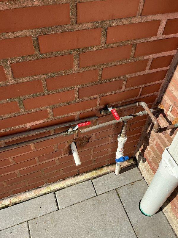 Installed exterior water supply system with new piping configuration including PVC and copper lines, mounted multiple shut-off valves with control handles at strategic points along brick wall, and added water filtration component to outdoor plumbing system. All connections properly fitted and secured with appropriate brackets, valves tested for proper operation and flow control.