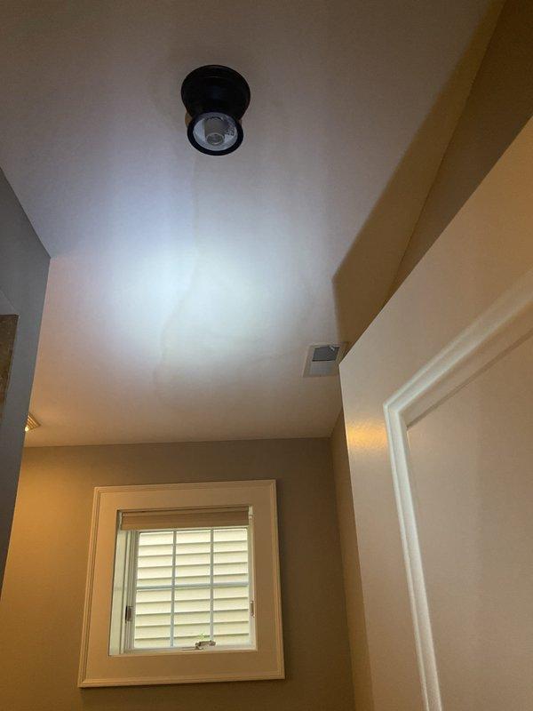 Responded to reported ceiling leak in residential property. Upon inspection, found affected area completely dry with no active water intrusion or visible ongoing damage. Examined light fixture where water had previously entered approximately one week prior to service call. Inspected ceiling surfaces, crown molding, and fixture mounting areas in hallway for signs of moisture, staining, or structural compromise. Documented conditions with photographs showing flush-mounted light fixtures and tray ceiling with decorative molding. No immediate plumbing repairs required as leak had ceased and no source of active water flow was detected during inspection period.