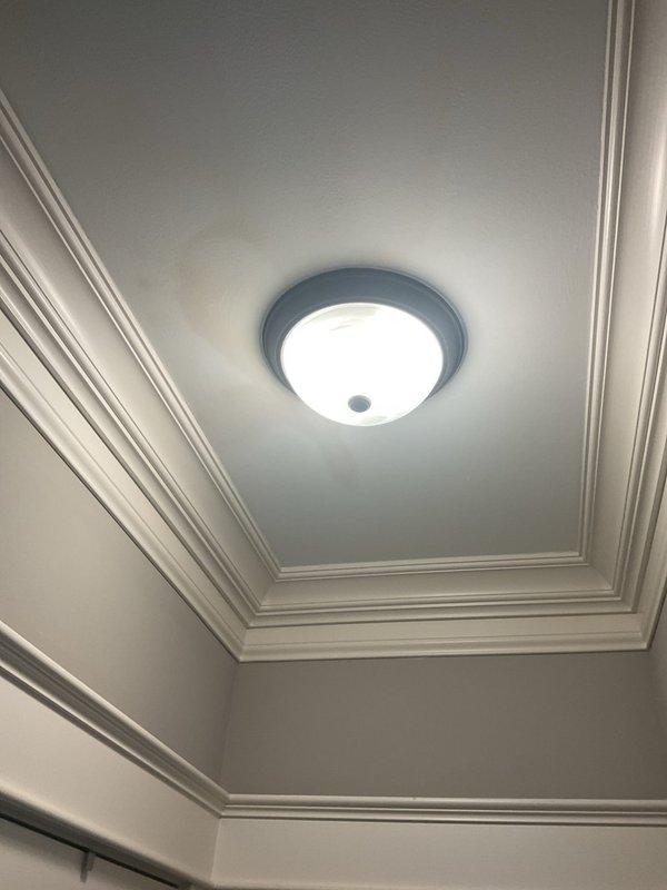 Responded to reported ceiling leak in residential property. Upon inspection, found affected area completely dry with no active water intrusion or visible ongoing damage. Examined light fixture where water had previously entered approximately one week prior to service call. Inspected ceiling surfaces, crown molding, and fixture mounting areas in hallway for signs of moisture, staining, or structural compromise. Documented conditions with photographs showing flush-mounted light fixtures and tray ceiling with decorative molding. No immediate plumbing repairs required as leak had ceased and no source of active water flow was detected during inspection period.