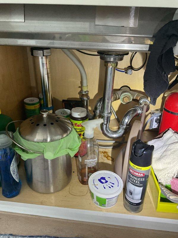 Responded to service call regarding persistent odor emanating from kitchen sink area for approximately two months. Inspected under-sink cabinet and plumbing configuration, including P-trap assembly, garbage disposal unit, and drain connections. Evaluated all visible plumbing components for proper installation, potential leaks, and sources of odor. Documented existing conditions of drain system and disposal unit for service records.