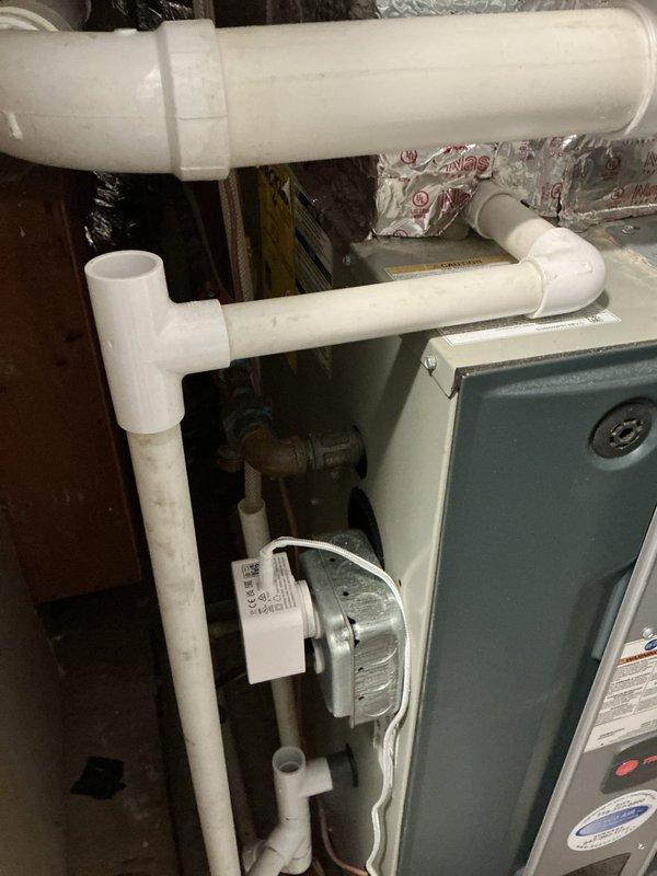 Installed new white PVC drainage piping system with multiple elbows and joints configured for proper condensate removal from HVAC equipment. Replaced existing aged metal P-trap assembly with updated plumbing components to ensure proper drainage function and prevent future deterioration issues in the mechanical room.