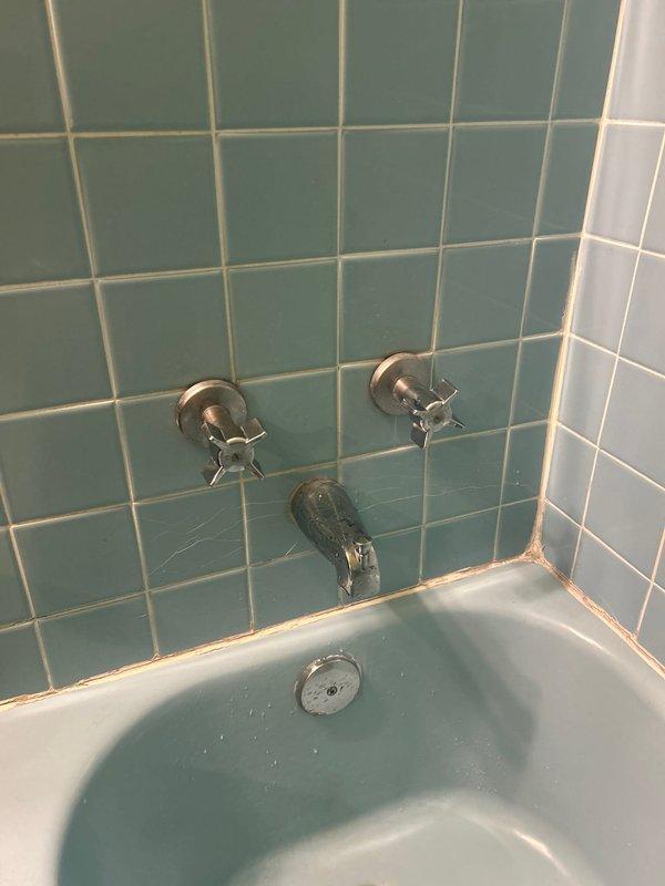 Responded to a shower hot water issue in a 40-year-old residence where the cartridge was suspected to be clogged due to extended non-use. Upon arrival, coordinated with the property association to shut off the water supply to the unit. Accessed the shower valve assembly behind the teal-tiled tub surround, which featured older-style chrome cross-handle faucet controls. Removed and inspected the hot water cartridge, confirming sediment buildup and debris accumulation from the prolonged period of inactivity. Cleaned the cartridge thoroughly, flushed the valve body to remove any remaining debris, and reinstalled the component. Restored water supply and tested both hot and cold water flow through the tub spout and shower head to verify proper operation and temperature control. System returned to normal functioning with adequate hot water delivery.