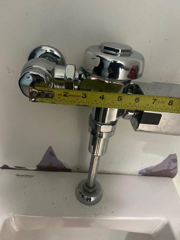 Provided estimate for commercial restroom plumbing repairs involving conversion of automatic flush valve to manual operation on urinal due to insufficient water flow to sensor mechanism. Assessment included evaluation of recurring drain clog requiring clearance. Documented existing automatic flush valve assembly with chrome sensor-equipped fixture and measured dimensions of current installation to specify appropriate manual flush valve replacement components.