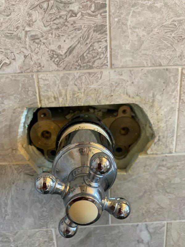 # Shower Faucet Replacement and Fixture Installation

Replaced existing shower faucet assembly with new chrome-plated two-handle fixture on tiled bathroom wall. Removed old mounting hardware and installed new brass mounting assembly with circular escutcheon plate, securing all connections through recessed wall opening. Installed complete shower system including three-valve control configuration with black escutcheon plate, separate volume control knob with decorative flange, and chrome shower arm. Connected handheld shower attachment with braided metal hose and verified proper water flow to both shower head and tub spout. Tested all valve controls for proper hot and cold water operation, checked for leaks at all connection points, and ensured complete functionality of the shower and bathtub system.