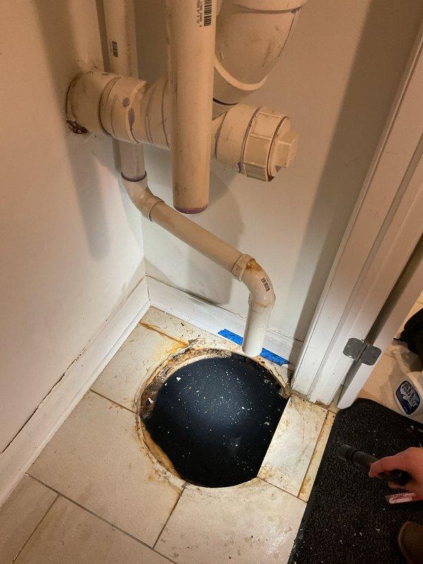 Responded to basement drain clog in 20-year-old residential property. Upon arrival, conducted camera inspection as requested to locate source of blockage. Investigation revealed severe subfloor water damage with significant deterioration around floor drain opening. Found standing water in crawl space beneath compromised plywood subfloor, indicating chronic drainage issue extending beyond initial clog complaint. 

Assessed PVC drainage system configuration and identified failed floor drain assembly as primary concern. Water intrusion had caused extensive structural damage to subfloor materials, requiring removal of deteriorated sections to access affected plumbing components. Documented conditions showing darkly stained and compromised flooring materials, standing water accumulation, and damaged drain infrastructure requiring immediate attention beyond standard drain clearing procedures.

Recommended comprehensive repair plan including subfloor replacement, drain line rehabilitation, an