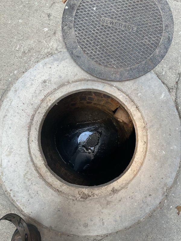 Responded to a drainage backup issue caused by a full catch basin affecting multiple drain points on the property. Upon inspection, located the sewer access point (dated 1995) and adjacent catch basin in the concrete surface area between buildings. The catch basin was found to be completely full with standing water, causing backup conditions through connected drain lines. Deployed equipment through the alleyway access point to address the blockage and restore proper drainage flow. Documented existing conditions showing the flooded catch basin and equipment setup for service records.