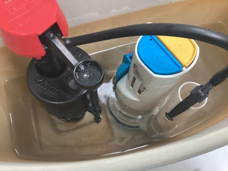 Responded to service call for two toilet issues in a 26-year-old residence with Toto fixtures. Successfully cleared clog on first-floor toilet that had been non-functional for three days. Inspected second-floor toilet with continuous running issue ongoing for several weeks; removed tank lid and identified worn flapper valve assembly showing discoloration and mineral buildup, along with aged fill valve components displaying brown staining and sediment accumulation. Photographed internal tank mechanisms documenting condition of flush valve, flapper, fill valve, and overflow tube. Water in tank exhibited brownish discoloration indicating mineral content and system age, consistent with original plumbing components in service for over two decades.