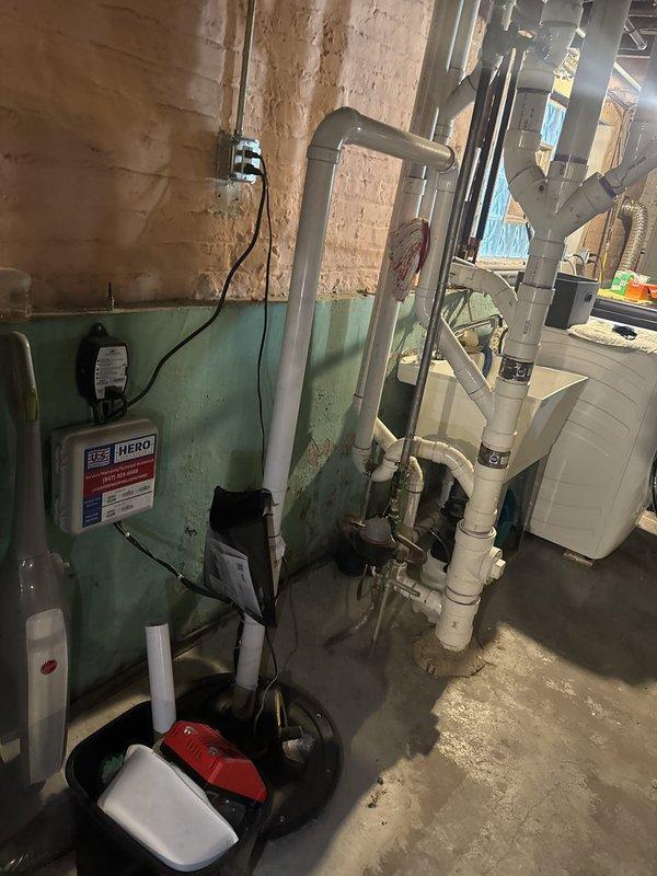 Completed financing arrangement for comprehensive plumbing system installation in basement mechanical room. New system includes boiler unit, sump pump with containment basin, water heater, and extensive PVC piping network with multiple branch connections throughout the space, requiring scheduling for final installation phase.