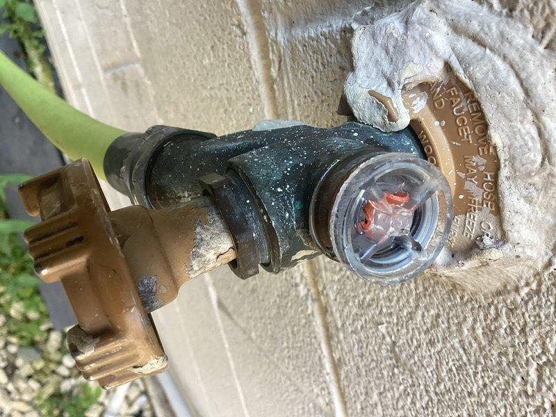 Responded to a heavy water leak at an exterior hose spigot equipped with a Woodford Model 17 anti-siphon valve. Upon inspection, found significant mineral deposits and weathering around the backflow prevention device, indicating prolonged exposure to leaking water. Replaced the faulty valve assembly with new brass fittings and installed proper flow control components to restore functionality and prevent future water waste.