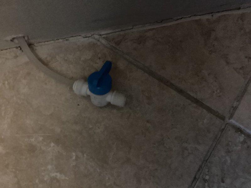 Installed water line hookup for new refrigerator in sixty-year-old residential unit. Connected supply line from existing shut-off valve to refrigerator ice maker and water dispenser using flexible braided stainless steel line with compression fittings. Verified existing ball valve with blue handle was functioning properly and accessible behind appliance. Tested connections for leaks, confirmed adequate water pressure, and ensured proper flow to refrigerator. All connections secured and system operational upon completion.