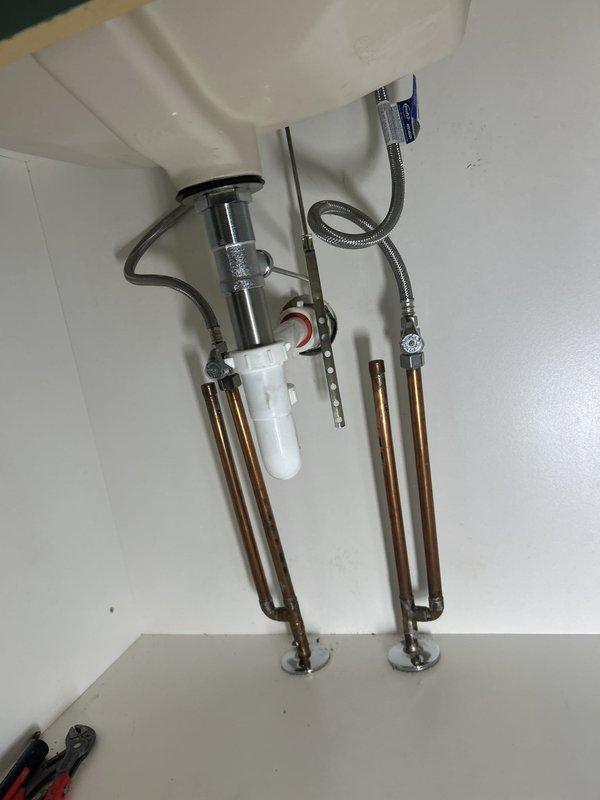 Completed bathroom faucet installation including new fixture mounting, P-trap assembly, and connection of braided stainless steel flexible water supply lines to existing copper supply pipes. All drain components and hot/cold water connections were properly secured with appropriate gaskets and fittings, system tested for leaks, and installation verified operational.