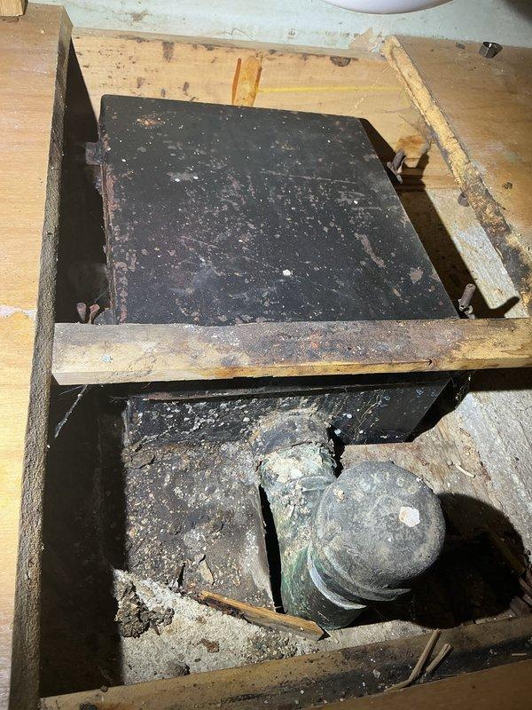 Completed plumbing inspection and documentation of existing conditions for a residential property. Assessed an aging floor access panel with significant rust and corrosion providing entry to below-grade utilities, noting deteriorated concrete surfaces and accumulated debris in the access cavity. Evaluated under-sink plumbing configuration including chrome P-trap assembly, copper supply lines, and flexible connector hoses to ensure proper drainage function and identify any potential maintenance concerns for the homeowner's future reference.