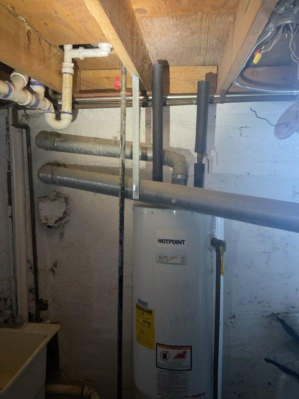 Conducted comprehensive assessment of residential water heating system following complete loss of hot water supply. Inspected existing Hotpoint water heater unit located in basement mechanical room and documented current installation configuration including all supply lines, drainage connections, and venting systems. Evaluated condition of copper supply piping, PVC drainage components, and existing shut-off valves. Photographed water heater unit showing manufacturer specifications, energy guide labels, and all plumbing connections to provide detailed documentation for replacement estimate. Assessed surrounding mechanical infrastructure including overhead floor joists, wall-mounted utilities, and available clearances for equipment replacement. Prepared comprehensive estimate for water heater replacement including all necessary materials and labor required to restore hot water service to the residence.
