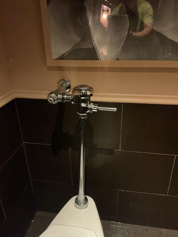 Responded to emergency call for overflowing toilet at commercial restaurant location. Upon arrival, found that a previous service provider had recently completed work, but toilet continued to overflow afterward. Customer reported a second toilet in different area of restaurant experiencing identical overflow issues and had shut off water supply as precautionary measure. Inspected flush valve assembly and fill valve mechanism on affected fixture. Photographed chrome flush valve with handle lever and vertical pipe connection, as well as fill valve assembly with hexagonal adjustment nut and brass push-connect fitting for documentation purposes. Identified malfunction in flush valve operation causing continuous water flow and overflow condition. Adjusted fill valve height and water level settings to prevent tank overfill. Tested flush cycle multiple times to ensure proper valve seating and complete shut-off after each flush. Restored water supply and verified no leakage or overflow occurri