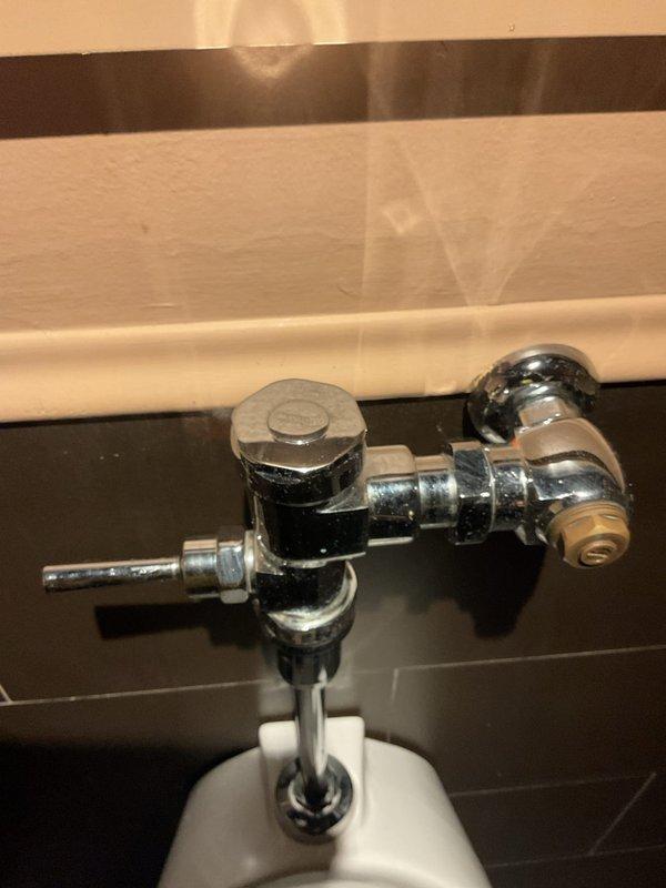 Responded to emergency call for overflowing toilet at commercial restaurant location. Upon arrival, found that a previous service provider had recently completed work, but toilet continued to overflow afterward. Customer reported a second toilet in different area of restaurant experiencing identical overflow issues and had shut off water supply as precautionary measure. Inspected flush valve assembly and fill valve mechanism on affected fixture. Photographed chrome flush valve with handle lever and vertical pipe connection, as well as fill valve assembly with hexagonal adjustment nut and brass push-connect fitting for documentation purposes. Identified malfunction in flush valve operation causing continuous water flow and overflow condition. Adjusted fill valve height and water level settings to prevent tank overfill. Tested flush cycle multiple times to ensure proper valve seating and complete shut-off after each flush. Restored water supply and verified no leakage or overflow occurri