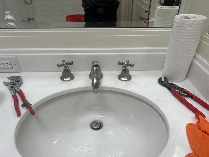 Completed installation of three-piece widespread lavatory faucet with cross handles and brushed nickel finish on bathroom vanity with undermount sink. Verified proper water flow, tested both hot and cold supply lines, and confirmed drain assembly operation with no leaks detected.