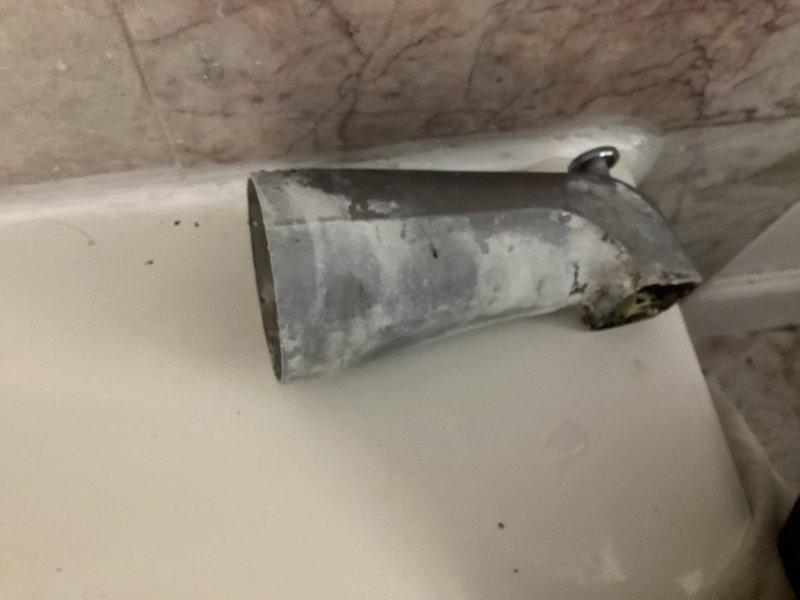 Completed plumbing estimate for shower diverter replacement in high-rise residential bathroom. Inspected chrome tub spout with faulty diverter mechanism and shower valve assembly mounted on marble-patterned tile wall. Customer informed of high-rise service fee waiver if proceeding with recommended repair work.