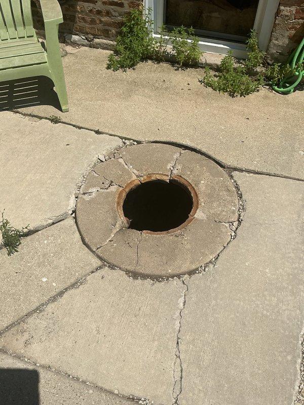 Completed installation of catch basin drainage system on exterior concrete patio area. Excavated existing deteriorated brick-lined shaft, removed accumulated debris and corroded metal components from bottom of structure, and installed new catch basin with proper drainage ring assembly. Addressed cracked and weathered concrete surrounding drain opening to ensure proper water flow and structural integrity of drainage system.