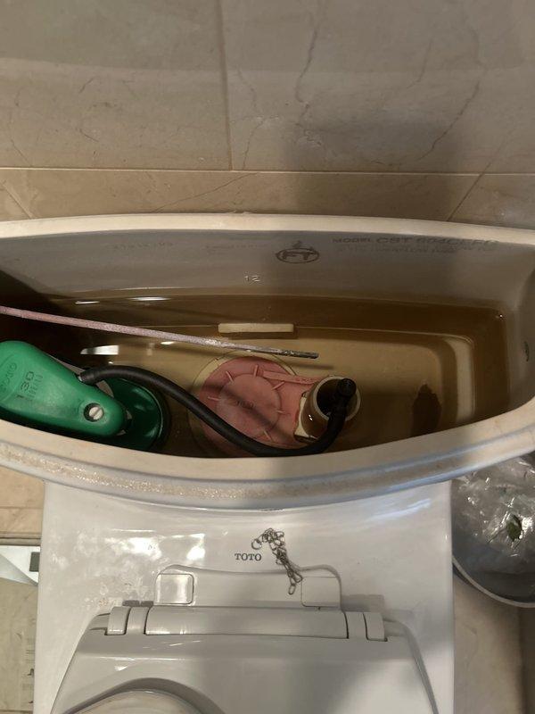Responded to service call for toilet with faulty gasket requiring replacement. Upon arrival, inspected TOTO brand toilet with integrated bidet seat attachment. Removed tank lid to assess internal components and flushing mechanism. Identified worn tank-to-bowl gasket as source of issue, evidenced by discolored water in tank and visible deterioration of seal. Documented existing conditions with photographs showing float assembly, flush valve mechanism, overflow tube, and connecting hardware. Evaluated bidet seat functionality to ensure no interference with repair work. Replaced defective gasket with new component to restore proper seal between tank and bowl. Tested flush mechanism and verified leak-free operation. Reinstalled tank lid and confirmed all components functioning correctly.