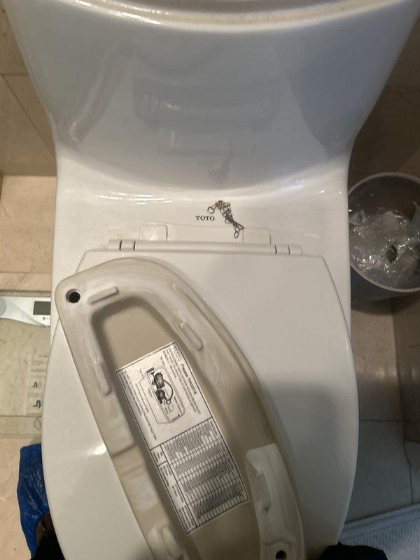 Responded to service call for toilet with faulty gasket requiring replacement. Upon arrival, inspected TOTO brand toilet with integrated bidet seat attachment. Removed tank lid to assess internal components and flushing mechanism. Identified worn tank-to-bowl gasket as source of issue, evidenced by discolored water in tank and visible deterioration of seal. Documented existing conditions with photographs showing float assembly, flush valve mechanism, overflow tube, and connecting hardware. Evaluated bidet seat functionality to ensure no interference with repair work. Replaced defective gasket with new component to restore proper seal between tank and bowl. Tested flush mechanism and verified leak-free operation. Reinstalled tank lid and confirmed all components functioning correctly.