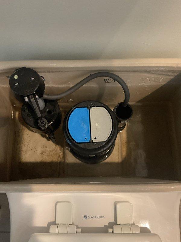 Responded to service call for low water pressure affecting toilet fill operation following previous water main repair work. Upon inspection, found Glacier Bay dual-flush toilet with insufficient tank refill despite adequate household water pressure. Examined internal tank components including fill valve assembly, flush valve mechanism, and supply line connections. Identified restricted flow through fill valve, likely due to debris accumulation from previous main line break and repair activities. Adjusted fill valve settings and cleared obstruction from valve inlet screen. Tested flush cycle multiple times to verify proper tank refill and water level restoration. Documented existing tank components and water quality conditions with photographs for service records.