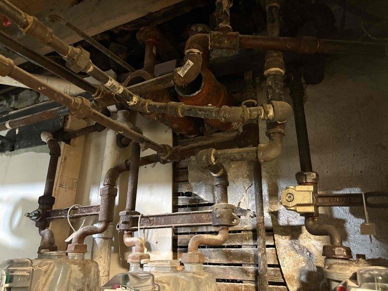 Performed comprehensive pressure testing on residential plumbing system including complex manifold assembly with multiple copper and brass pipe connections. System tested successfully with all connections, fittings, and aged piping holding proper pressure without leaks detected.