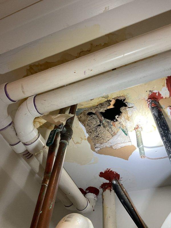 Responded to a clogged floor drain concern in the HVAC utility room. Upon inspection, identified active water damage to ceiling materials with visible staining and deterioration, indicating a leak from the floor above was potentially contributing to drainage issues in the lower level. Documented existing plumbing configuration including water heater connections, copper supply lines, and PVC drainage system for further evaluation and estimate preparation.