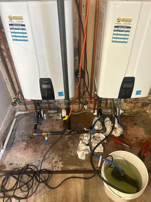 Performed comprehensive VIP maintenance service on dual Coorie tankless water heater system. Conducted complete descaling and flushing procedure using circulation pump and cleaning solution to remove mineral buildup and maintain optimal heat exchanger efficiency. Inspected all plumbing connections, shut-off valves with red handles, brass fittings, and multi-colored supply lines for proper operation and potential leaks. Verified digital control panel functionality on both units and confirmed Energy Star rated performance standards were maintained. Examined venting system including white PVC exhaust pipes and metallic flexible ductwork for proper installation and clearances. Assessed overall system performance and confirmed both tankless units operating within manufacturer specifications.