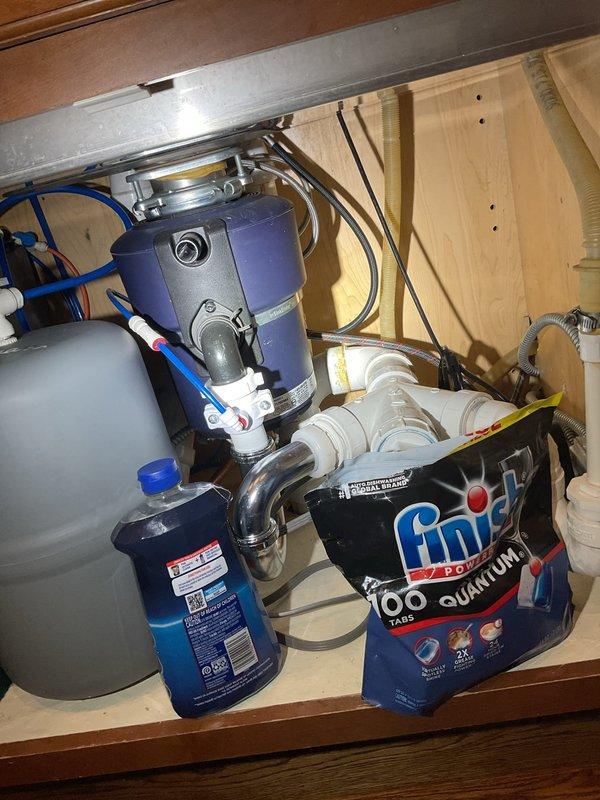 Responded to drainage issue in powder bathroom. Upon inspection, examined under-sink plumbing configuration including garbage disposal unit, P-trap assembly, and drain connections. Verified proper installation of chrome pop-up drain assembly with lift rod mechanism and confirmed white PVC drainage system connections. Inspected disposal mounting, water supply lines, and all pipe connections for leaks or blockages. Documented existing plumbing configuration showing disposal unit connected to drain system with appropriate trap configuration and venting.