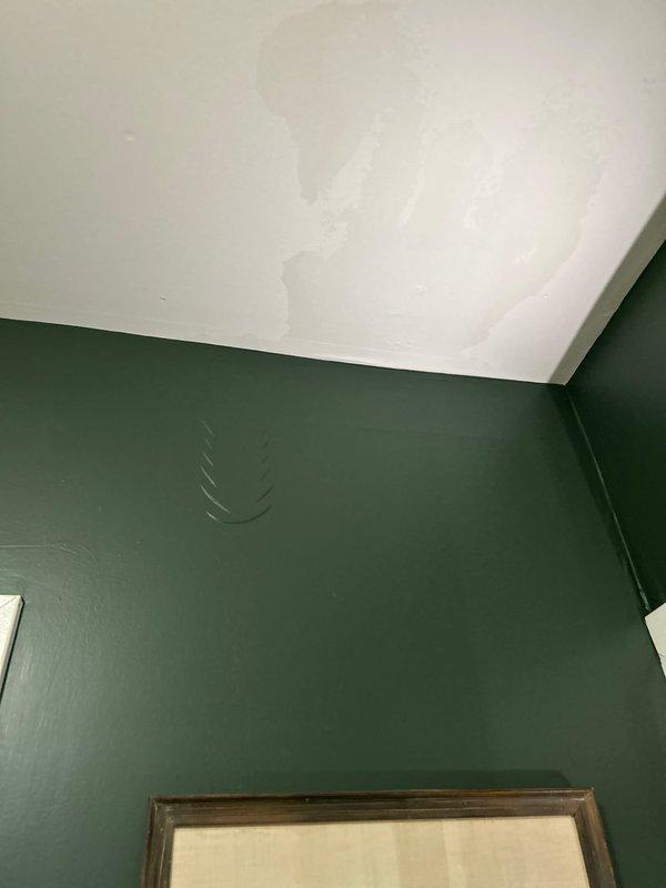 Responded to water leak investigation in basement near boiler system. Performed thorough visual inspection and leak tracing to identify source of moisture intrusion reported as originating from upper level. Inspection revealed active water damage on ceiling surfaces with extensive staining patterns indicating ongoing moisture penetration from above. Documented ceiling discoloration and water intrusion evidence in corner junction area where walls meet ceiling. Traced leak path from basement ceiling through utility and storage areas. Photographed all affected areas showing water damage progression and moisture patterns for diagnostic purposes and future reference. Advised customer of findings and recommended further investigation of upper-level plumbing fixtures, supply lines, or potential roof/exterior water intrusion points directly above damaged ceiling area to isolate exact leak source for proper remediation.