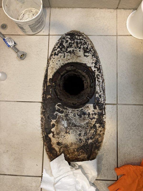 Responded to service call for toilet leaking from base. Upon arrival, removed existing toilet to diagnose source of leak. Inspection revealed severely corroded toilet flange with extensive rust, mineral buildup, and structural deterioration that compromised the seal between toilet and drain pipe. The existing flange was beyond repair due to long-term moisture exposure and corrosion.

Removed and disposed of failed flange assembly. Cleaned drain opening and surrounding area to ensure proper surface preparation. Installed new toilet flange with secure mounting to subfloor. Applied new wax ring seal and reinstalled toilet, ensuring proper alignment with drain. Connected water supply line and tested for leaks. Verified toilet operates correctly with no water leakage at base. Left work area clean and operational.
