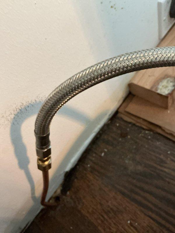 Responded to priority water leak behind refrigerator in century-old home where quarter-inch copper water line had been leaking for five days. Replaced failed copper supply line with new braided stainless steel flex hose, installed proper brass fittings, and tested connections for leaks. System restored to full operation with no active leaks detected upon completion.