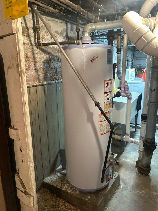 Conducted on-site assessment for water heater replacement in basement of 120-year-old residential property. Evaluated existing gas-fired water heater unit installed on concrete floor with copper supply lines, gas control valve assembly, and venting system. Documented current installation configuration including plumbing connections, gas line routing, temperature and pressure relief valve positioning, and exhaust venting through existing ductwork. Inspected surrounding utility area conditions including exposed stone foundation walls, clearance requirements, and access points for replacement work. Photographed existing unit specifications, manufacturer labels, energy guide information, and all visible piping connections to ensure proper sizing and specifications for replacement unit. Assessed gas supply line, cold water inlet, hot water outlet, and condensate drain configurations. Verified existing installation meets current code requirements for combustion air, venting, and safety clear