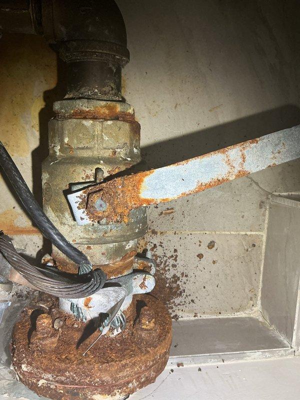 Conducted plumbing assessment for water service upgrade involving meter and valve replacement. Documented severely corroded water meter assembly with extensive rust deterioration on piping connections, circular flange, and mounting hardware, indicating prolonged moisture exposure and immediate need for system modernization. Provided estimate for complete water meter and valve upgrade to restore proper functionality and prevent potential service failure.