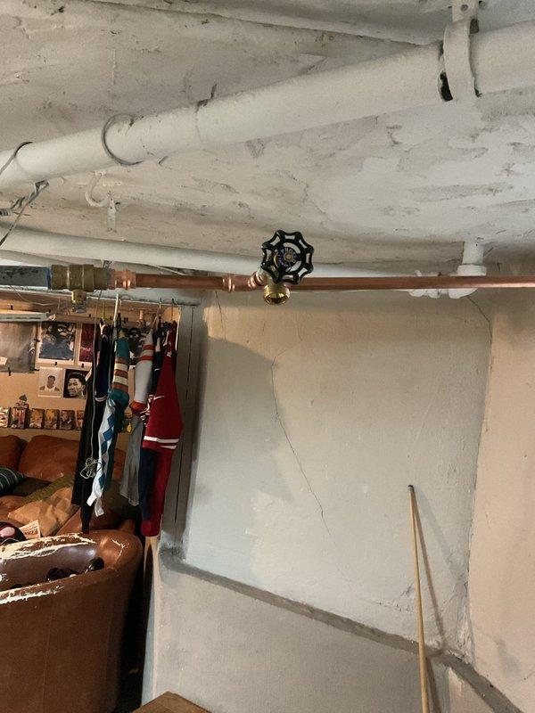 Replaced defective outdoor water spigot (hose bib) mounted on front exterior wall of residence. Shut off water supply at interior copper supply line using existing shut-off valve in basement utility area. Removed old corroded copper fixture from exterior wall penetration and installed new frost-free sillcock with proper pitch for drainage. Verified proper operation of new hose connection and checked for leaks at both exterior mounting point and interior shut-off valve. Restored water supply and confirmed system integrity.