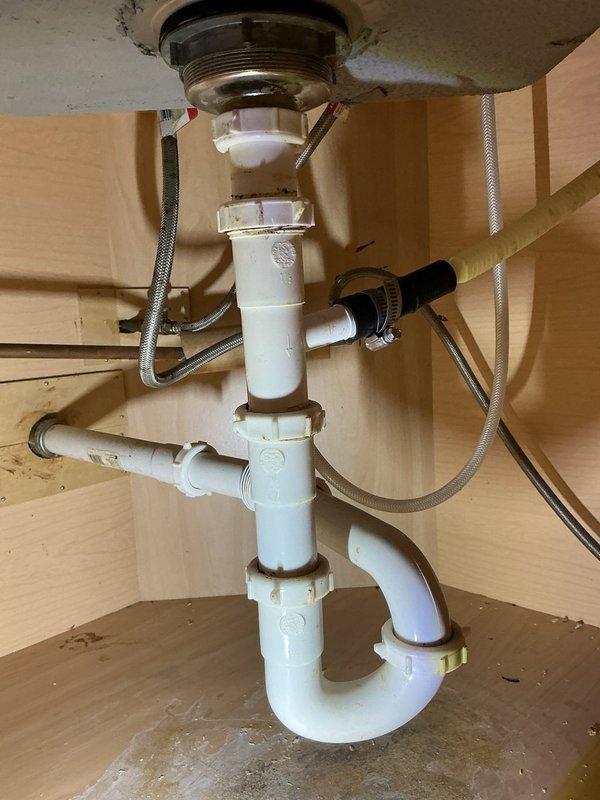 Responded to service call for Gerber single handle kitchen faucet model #40-103 experiencing high-pitched whining noise during hot water operation. Diagnosed cartridge valve issue causing whistling sound that intensified at full flow and diminished when partially closed. Inspected and verified aerator filter was clean as previously checked by homeowner. Consulted manufacturer installation guide and disassembled faucet handle assembly to access internal cartridge. Replaced defective cartridge with OEM replacement part to eliminate noise issue. Additionally, inspected loose first floor kitchen sink P-trap assembly where PVC joint had separated. Tightened slip-joint connections on white PVC P-trap configuration and verified proper seal at all threaded couplings. Tested drain system for leaks and confirmed proper water flow. Cycled faucet through hot and cold water at various flow rates to verify elimination of whining noise and ensure proper cartridge operation.