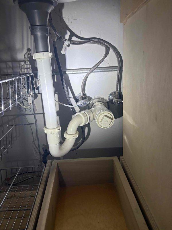 Technician conducted on-site evaluation for kitchen and laundry area plumbing systems. Assessment included inspection of existing under-sink drainage configuration with garbage disposal unit, PVC trap assembly, and dishwasher connection points, as well as evaluation of laundry room utility connections for stacked washer and dryer installation. Documented current plumbing conditions and photographed installations to develop comprehensive piping estimate for necessary modifications or repairs.