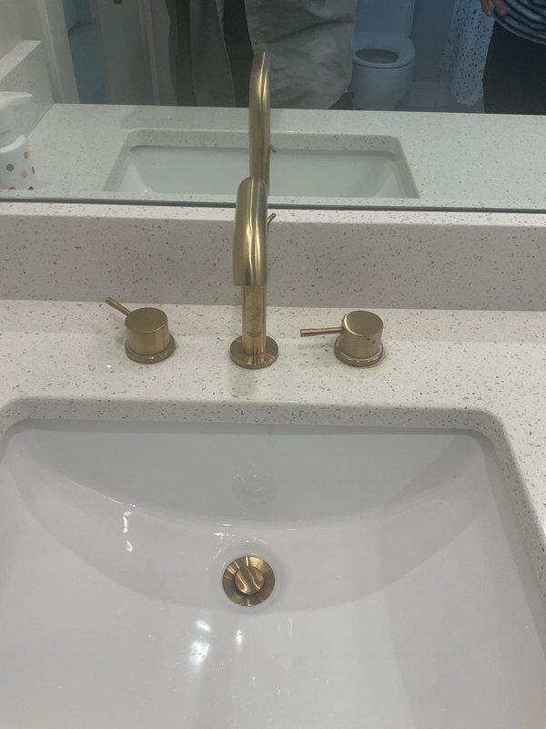 Responded to service call for bathroom faucet handle that would not turn off properly and leaking toilet. Inspected the three-piece brushed brass faucet assembly on undermount sink and identified worn valve cartridge preventing proper shutoff. Replaced faulty cartridge and tested operation of both handles to ensure proper water flow control. Diagnosed toilet leak, identified failed wax ring seal at base, and replaced wax ring to eliminate water seepage. Verified all fixtures functioning properly with no active leaks upon completion.