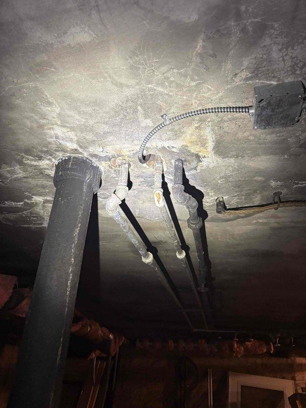 Responded to priority service call for low water pressure and lack of hot water at residential property. Previous contractor had identified rust buildup and clog in piping system but declined to perform repairs. Upon arrival, conducted thorough inspection of basement plumbing infrastructure, including exposed supply lines, distribution piping, and water heating system. Assessed condition of aging galvanized steel pipes showing visible corrosion and rust accumulation throughout the water supply network. Evaluated complex piping configuration including multiple branch lines, vertical risers, and horizontal runs servicing the property. Documented extensive rust deposits and sediment blockage restricting water flow through compromised sections of piping. Inspected electrical panel and utility connections in basement area to assess overall mechanical systems condition. Photographed affected piping sections, ceiling-mounted infrastructure, and utility room layout for documentation purposes. 